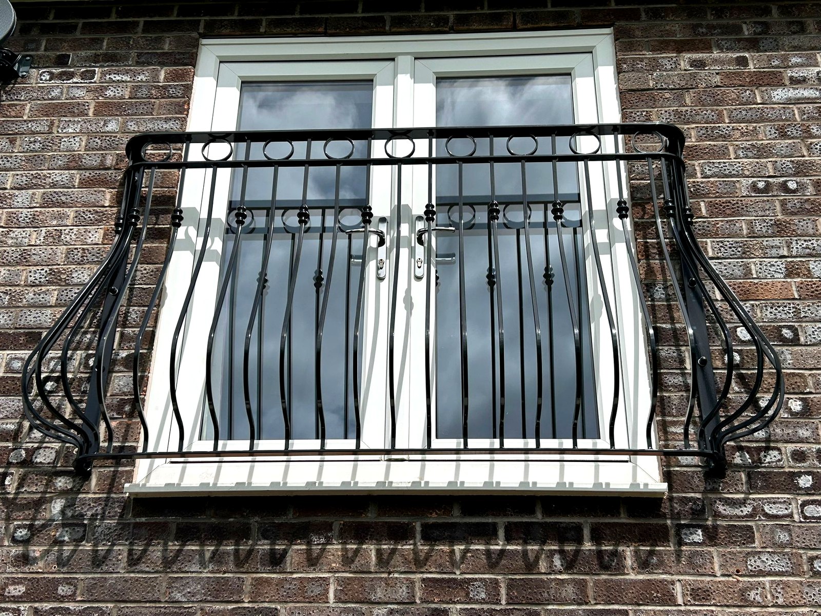 Black Regency-style ornate metal Juliet balcony with scrollwork